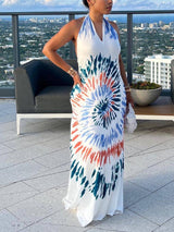 Side view of a woman in a white tie-dye maxi dress with a halter neckline.