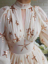 Front view of the bodice and neckline of a white chiffon gown with starfish sequin embellishments.