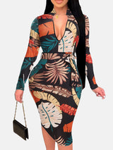 Woman wearing a black midi dress with a colorful leaf print, V-neck, long sleeves, and a belted waist.