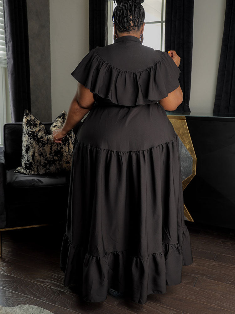 Back view of a woman in a black ruffled maxi dress.