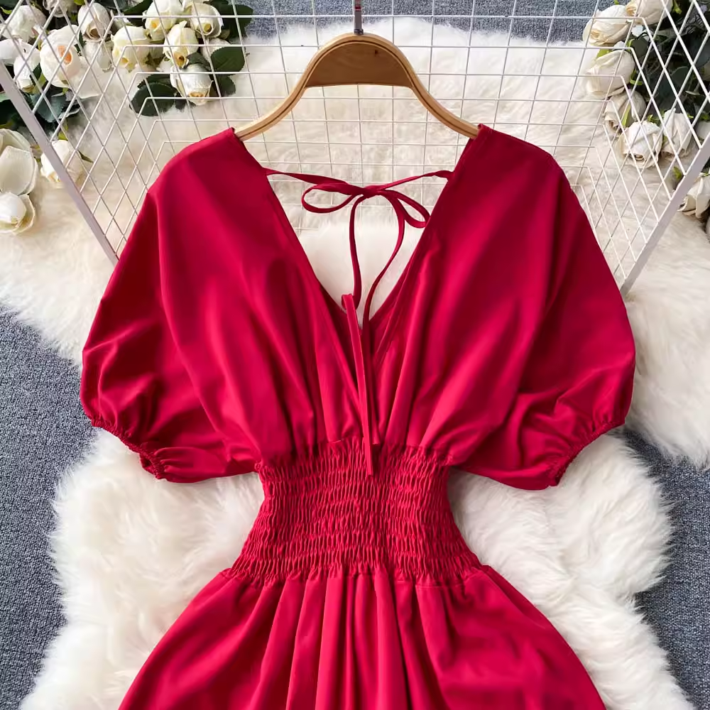 Close-up of the red maxi dress showing the V-neckline, smocked waist, and puff sleeves