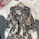 Back view of a black and white floral embroidered midi dress with sheer puff sleeves and sequin details.
