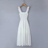 White eyelet maxi dress hanging on a wooden hanger against a grey background