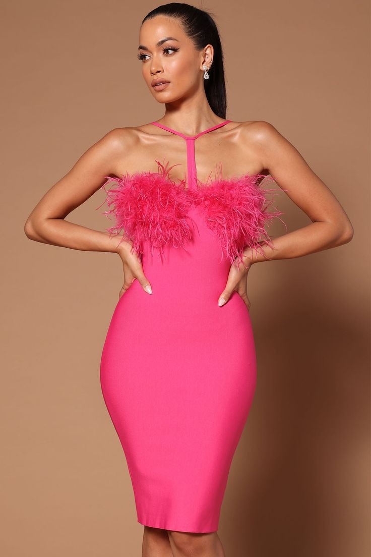 Close-up of a woman in a hot pink bandage midi dress with feather trim and a halter neckline, hands on hips.