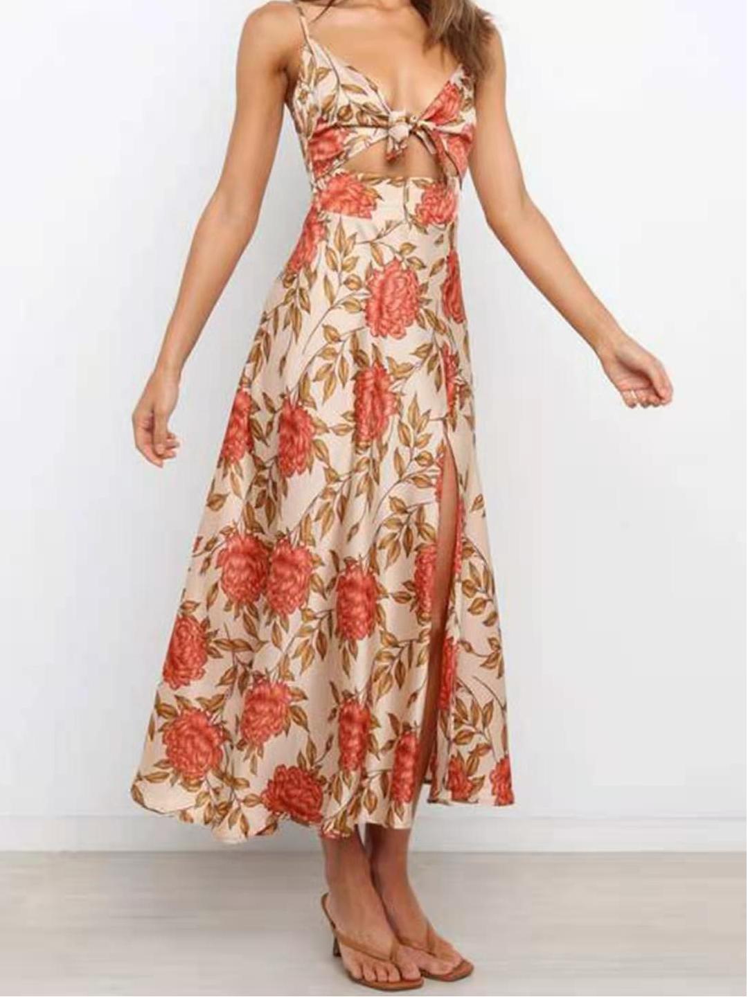 Woman wearing a floral print satin dress with a cut-out and thigh-high slit, standing with her arms outstretched.