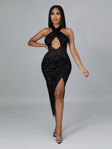 Woman wearing a black sequined halter neck dress with a plunging neckline and high slit.
