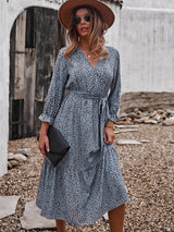 Woman wearing a light blue and brown polka dot midi dress, brown hat, and sunglasses.