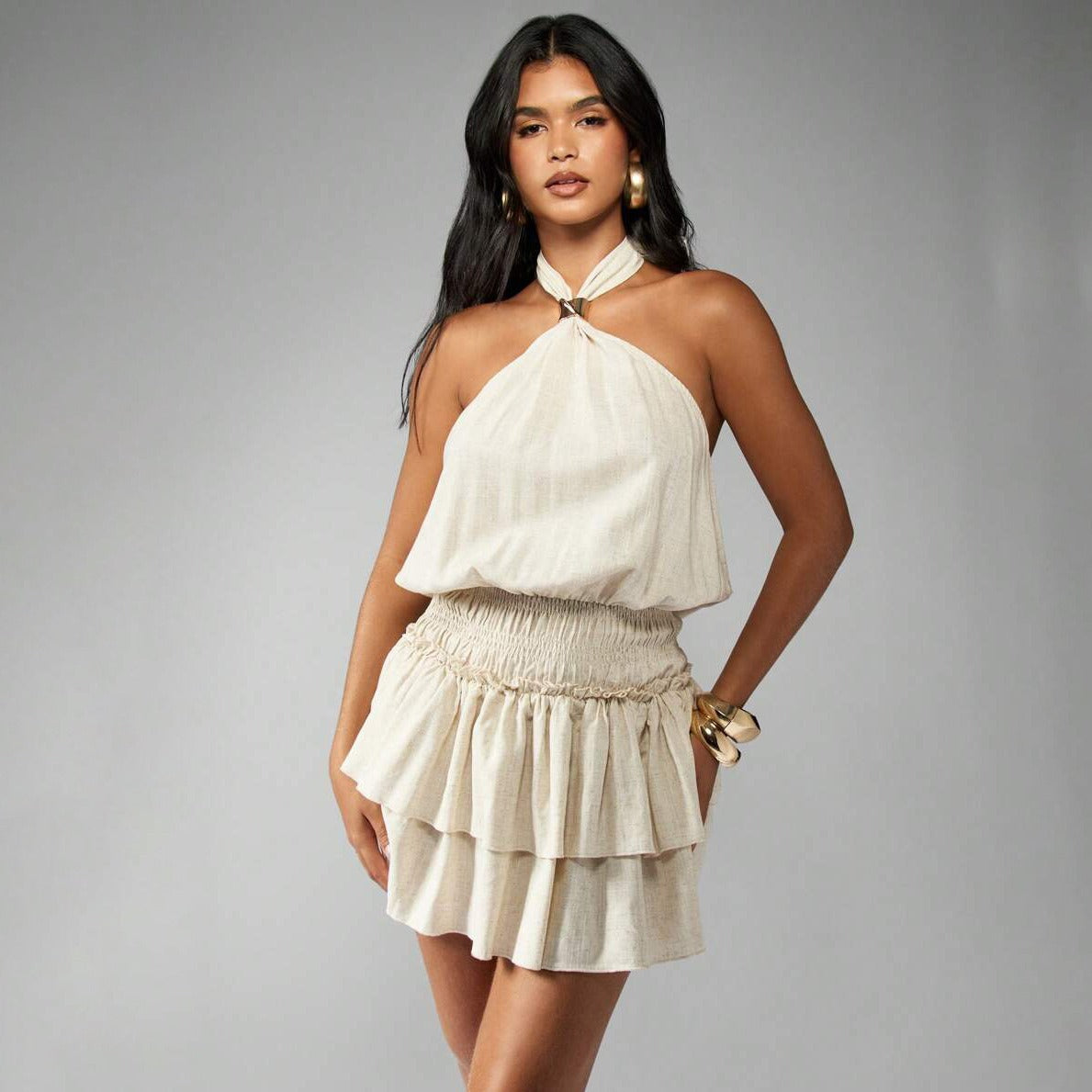 Close-up of the cream tiered mini dress showing the halter neckline and smocked waist.