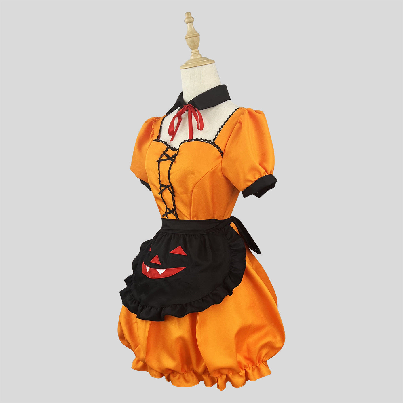 Side view of an orange Halloween costume with a black apron, on a mannequin against a grey background