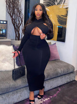Woman in a black long-sleeved maxi dress with a cutout and crisscross neckline.