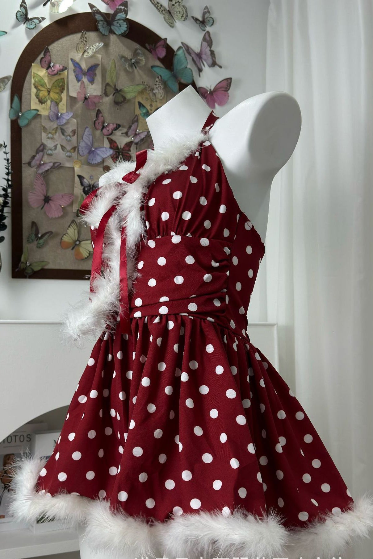 side view of a red and white polka dot halter dress with faux fur trim on a mannequin