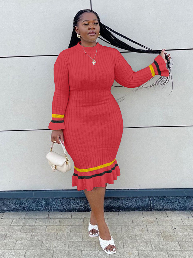 Woman in a red ribbed knit midi dress with long sleeves and striped details, posing with her hair.