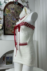 Side profile of a white strapless dress with red plaid trim and red ribbon accents, displayed on a mannequin.
