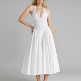 Woman wearing a white halter neck midi dress with a pleated skirt.