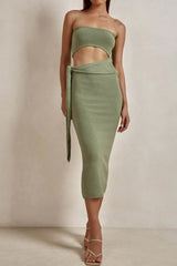Woman wearing a sage green strapless knit crop top and matching midi skirt with a tie waist and side slit.