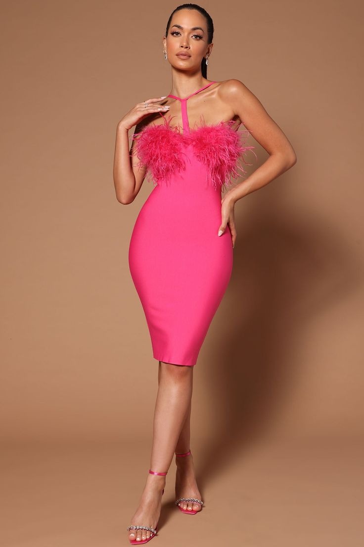 Woman wearing a hot pink bandage midi dress with feather trim and a halter neckline, standing with hands on hips.