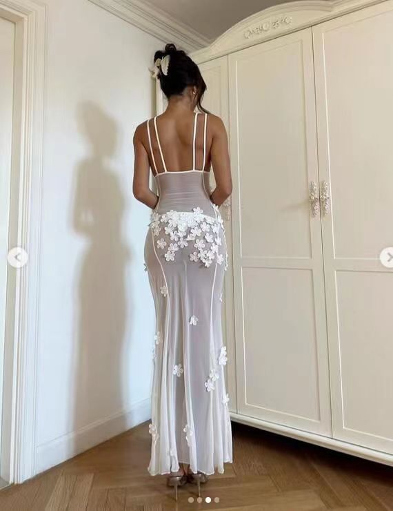 Rear view of a woman wearing a long, sheer white floral applique dress.