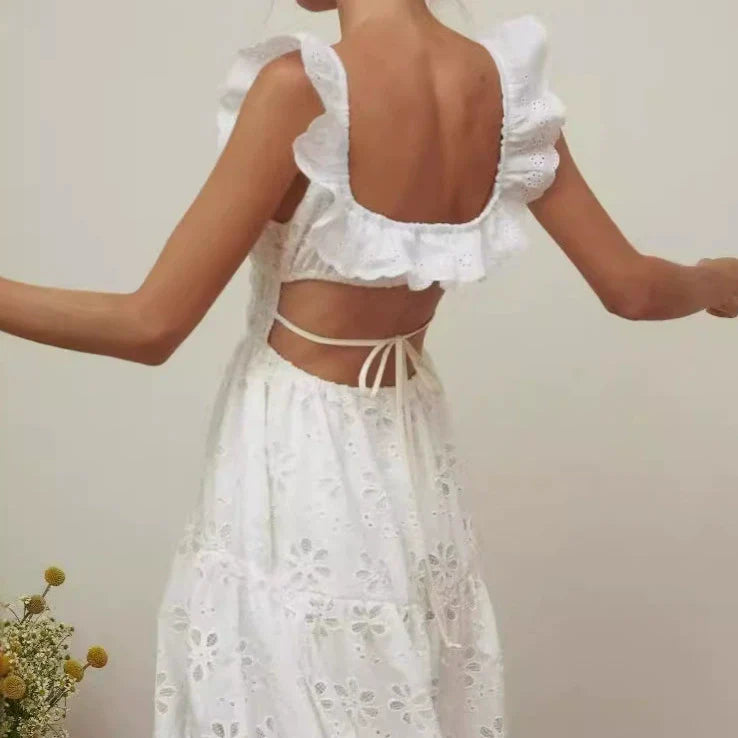 Back view of a woman wearing a white eyelet maxi dress with an open back and tie closure