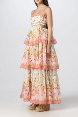 Side view of a woman wearing a floral print maxi dress with a tiered skirt and cut-out details