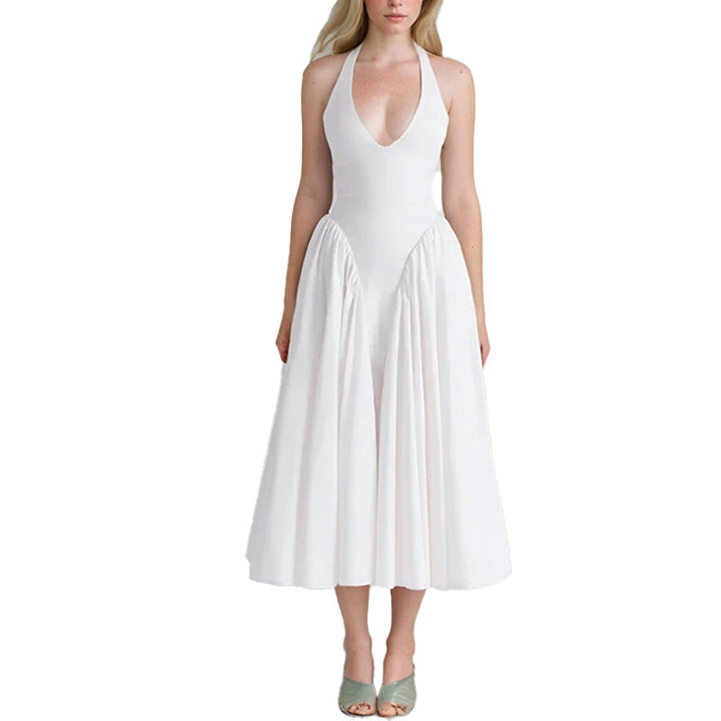 Front view of a woman wearing a white halter neck midi dress with a deep V-neckline and full skirt, against a gray background.