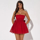 Woman wearing a red strapless sparkly mini dress with a cinched waist, flared skirt, and a large bow detail on the back