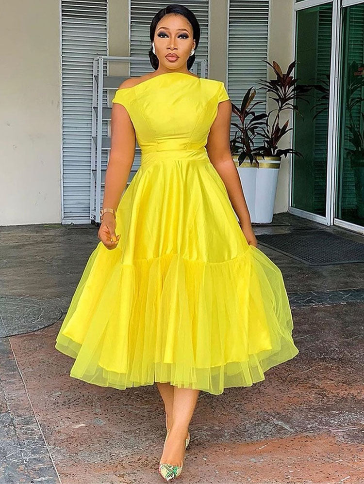 woman wearing a bright yellow fit and flare dress with an asymmetrical neckline and a tiered tulle skirt