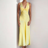Yellow satin maxi dress with a twisted halter neckline and flowing skirt