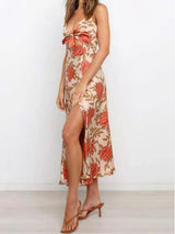 Woman wearing a floral print satin dress with a cut-out and thigh-high slit, standing in a side profile, showcasing the slit.