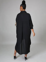 Back view of a woman in a black shirt dress with leopard print detail on the sleeve and an asymmetrical hem.