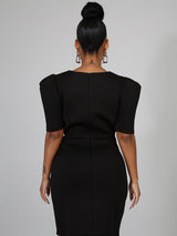 Back view of a woman in a black knee-length dress with puffed shoulders.