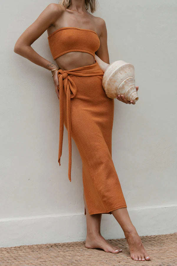 Close-up of a woman's torso wearing an orange strapless knit crop top and matching midi skirt with a tie waist.