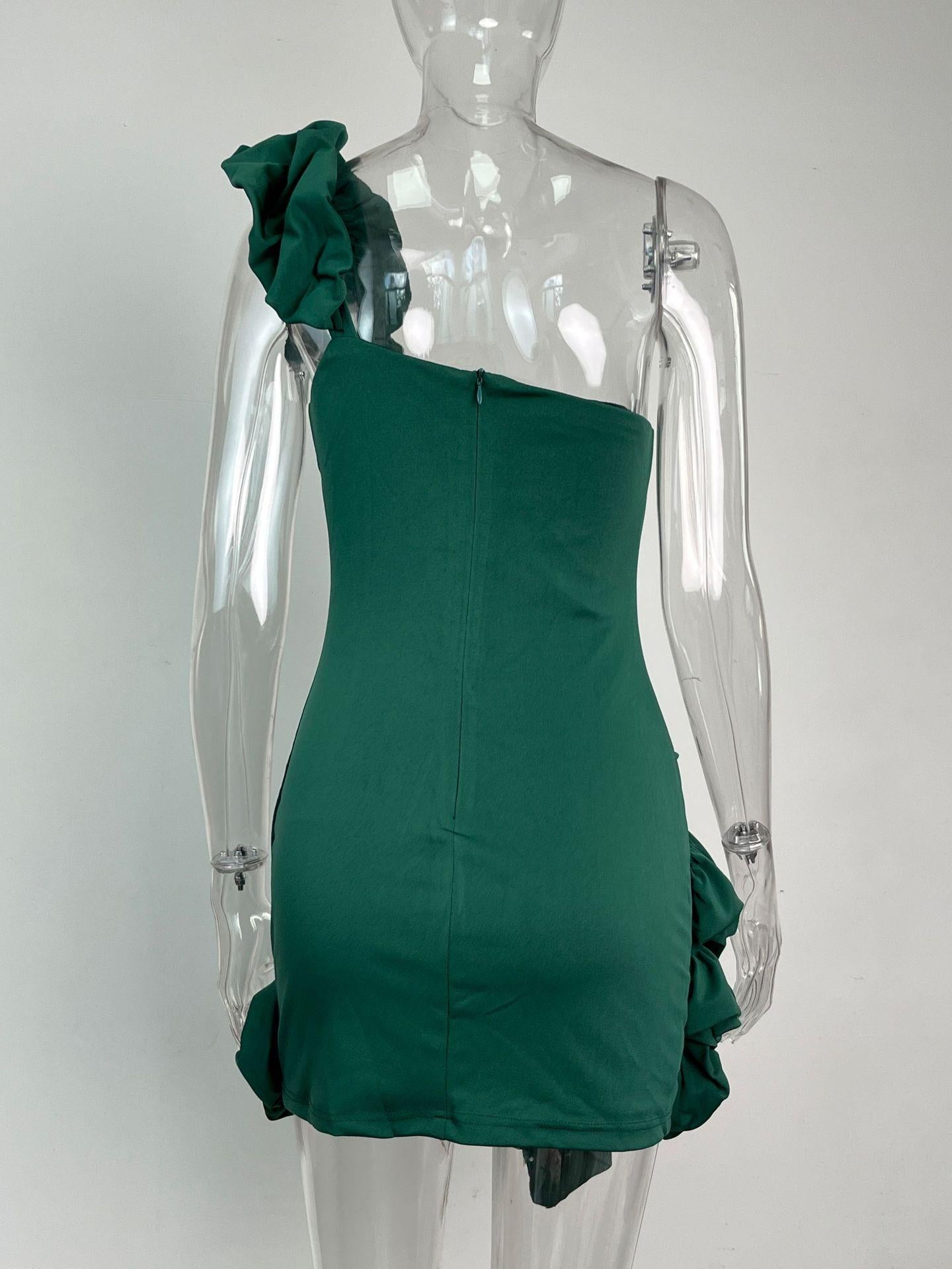 Back view of a green one-shoulder mini dress with a zipper closure and ruffle accents, shown on a mannequin.