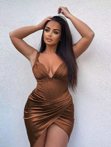 Woman with dark hair in a brown satin dress with a plunging neckline and high slit.
