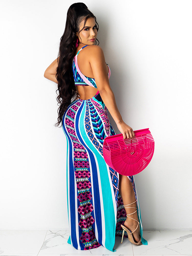 Back view of a woman wearing a colorful geometric print maxi dress with spaghetti straps and a side slit, holding a pink fan-shaped bag.