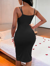 Back view of a woman in a black ribbed knit bodycon midi dress with spaghetti straps and a fitted silhouette.