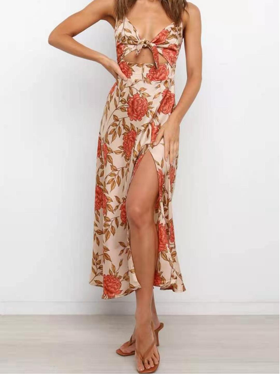 Woman wearing a floral print satin dress with a cut-out and thigh-high slit, standing with her hands on her hips.