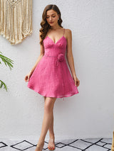 Full-length shot of a woman in a pink textured dress with a floral waist detail.