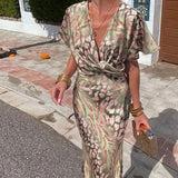 Woman wearing a green and pink animal print satin maxi dress with a V-neckline and twisted front detail.