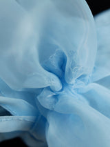Close-up of the light blue sheer organza fabric with ruffles and ties on the sleeves