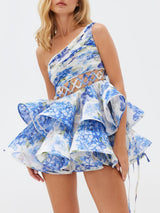 Close-up of a blue floral print one-shoulder mini dress with a ruffled skirt.