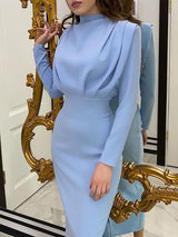 A woman wearing a light blue long-sleeved draped neck sheath dress.