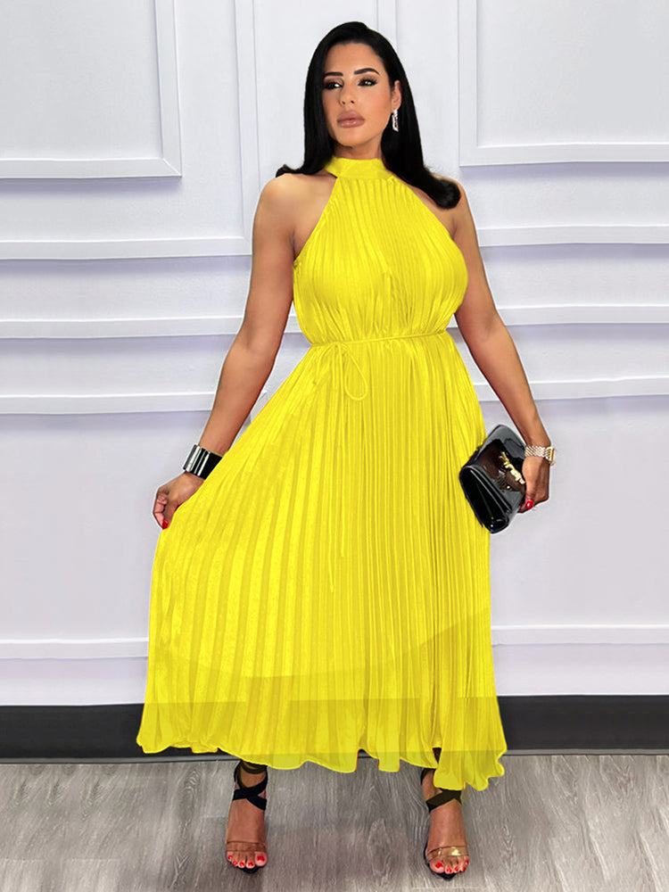 Woman in a yellow pleated midi dress holding a clutch