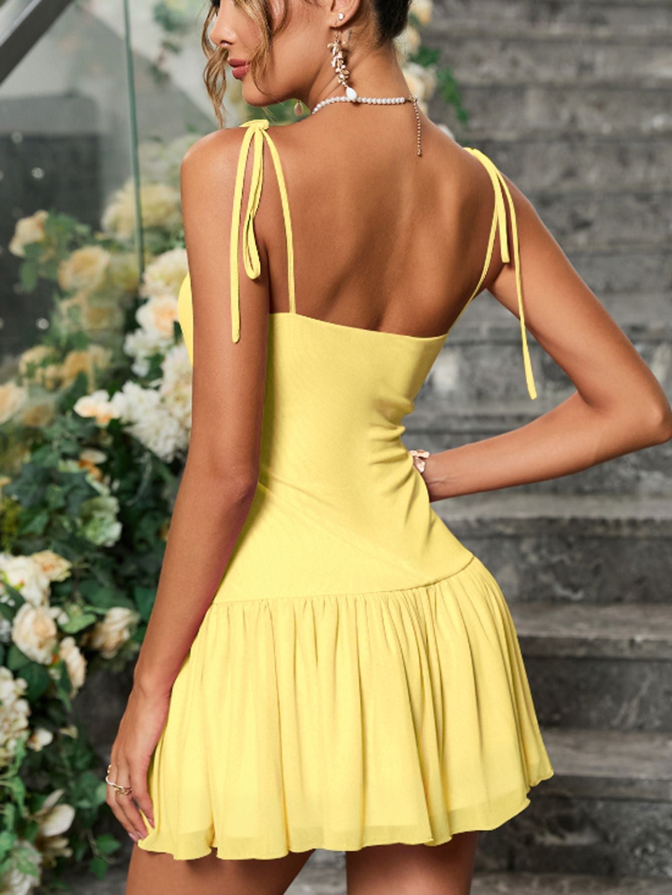 back view of a woman in a yellow ruched chiffon dress showing tie shoulder straps