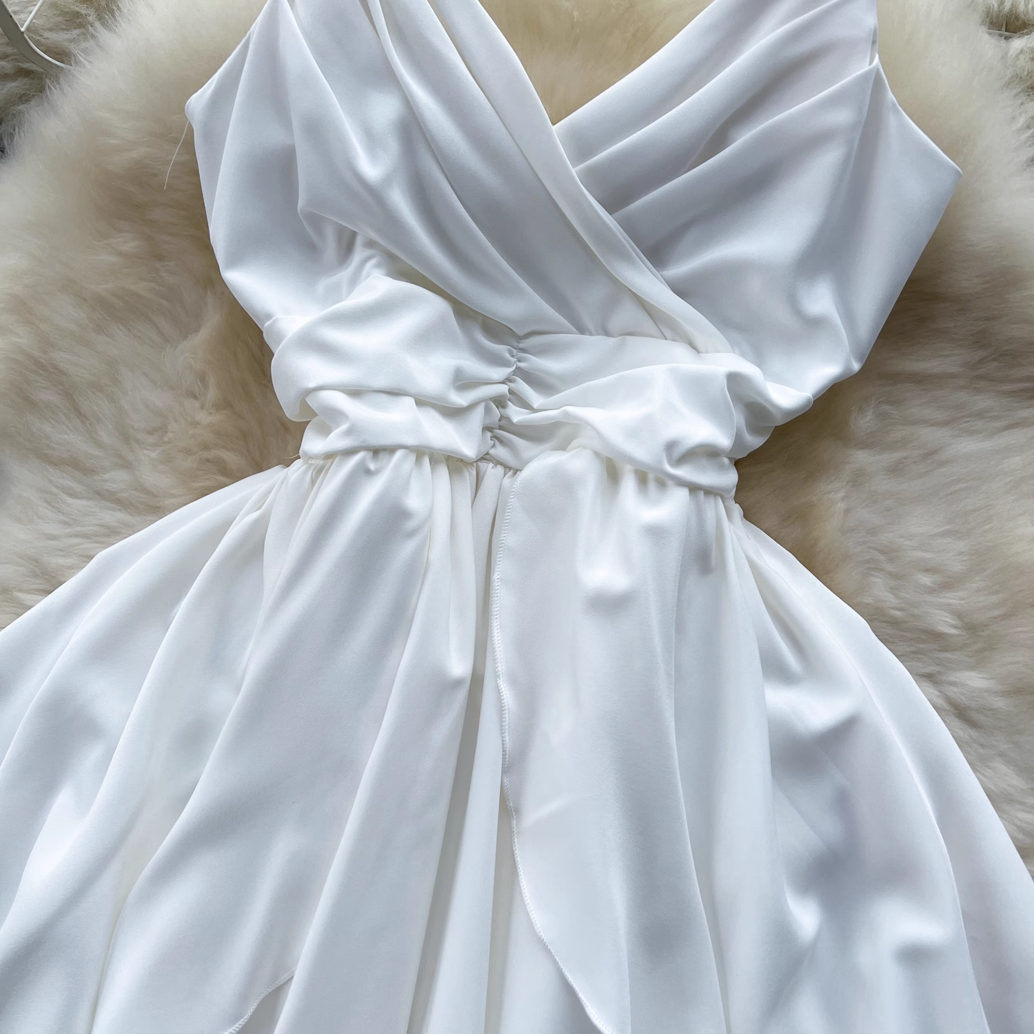 Close-up of the ruched bust and waist detail on a white satin cami dress.