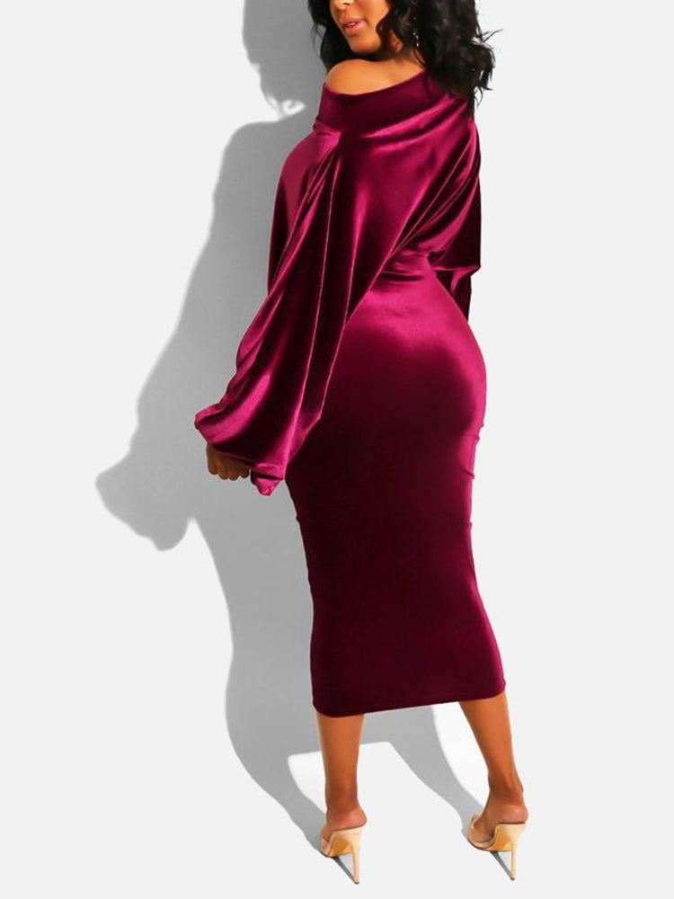 Woman from the back wearing a burgundy velvet off-the-shoulder midi dress with long sleeves and clear heels, posing against a white background.