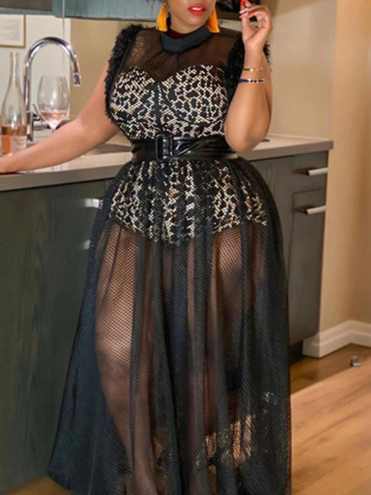 Woman wearing a leopard print top with a sheer black mesh overlay maxi skirt and a wide black belt, standing in a kitchen.