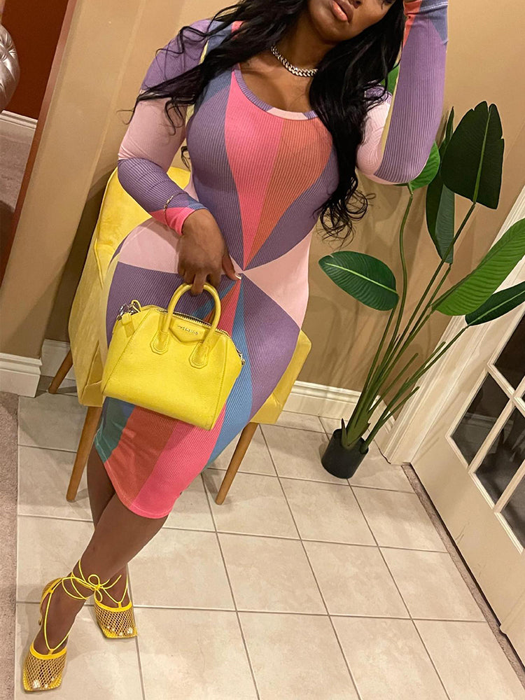 Woman wearing a long-sleeved, multi-colored geometric print bodycon dress with a crew neck, holding a yellow handbag and yellow strappy heels.