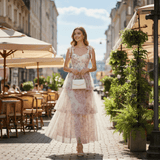 Woman in a floral tiered maxi dress walking on a cobblestone street.