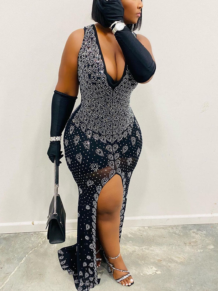 Full-length view of a woman wearing a black embellished mermaid gown with a thigh-high slit and matching gloves.