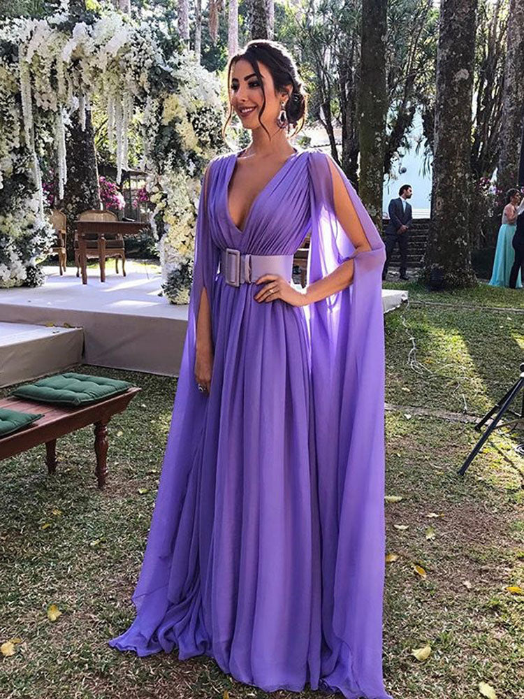 Woman in a long purple formal dress with cape sleeves and a white belt, standing outdoors